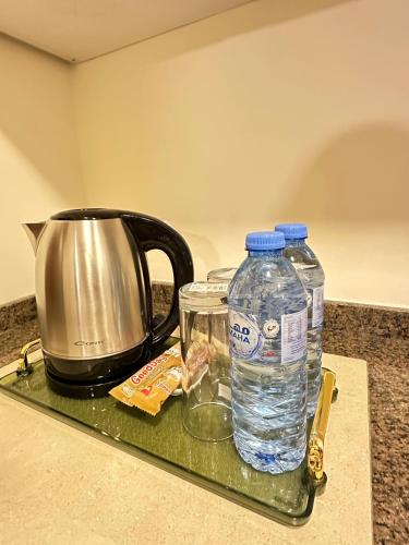 a tray with two bottles of water and a kettle at Londrina Hotel in Amman