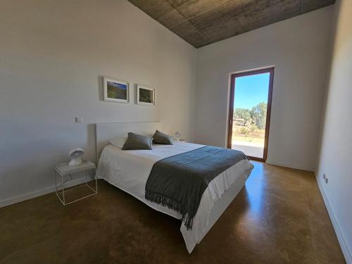 ein Schlafzimmer mit einem Bett und einem großen Fenster in der Unterkunft Casa de Mosqueirões in Santa Margarida da Serra