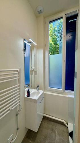 une salle de bain blanche avec un lavabo et une fenêtre dans l'établissement Studio 89 Albufera - Gare Vernon Giverny, à Vernon