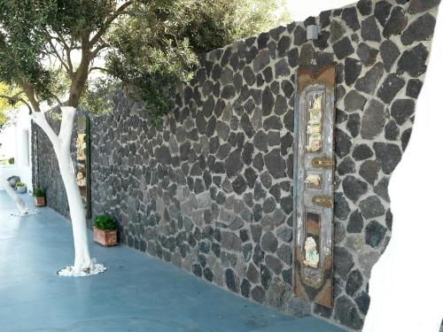 a stone wall with a tree next to it at San Marino Suites by Calm Collection in Fira