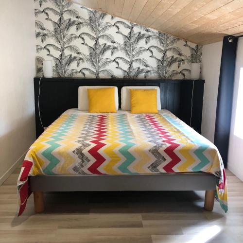 - un lit avec une couette colorée et 2 oreillers jaunes dans l'établissement L'Erable, à Beaussais