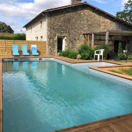une piscine avec des chaises bleues et une maison dans l'établissement L'Erable, à Beaussais