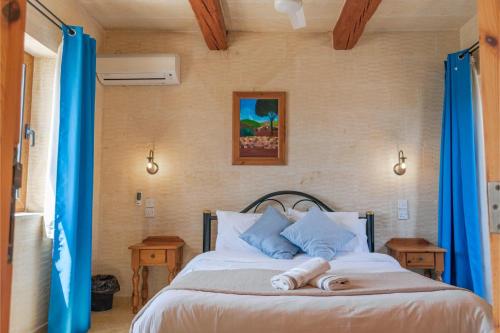 a bedroom with a bed with blue curtains at Ta Danjela Villa Sleeps 8 with Pool in Xagħra