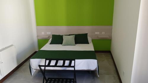 a green and white bedroom with a bed and a chair at Apartamento Sanin 3 in Lumbrales