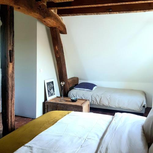 - une chambre avec 2 lits dans une pièce dotée de poutres apparentes dans l'établissement la maison haute, à Toucy