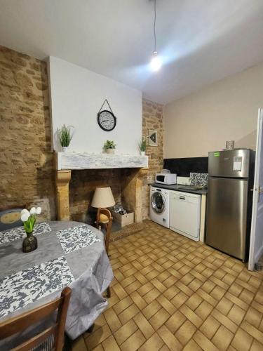 une petite cuisine avec une table et un réfrigérateur dans l'établissement Gite de la Marquise, Maison périgourdine de charme, en pierre, à 2min à pieds de la cité médiévale de Sarlat, à Sarlat-la-Canéda