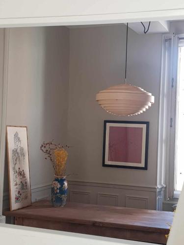 - un salon avec une table et une lampe pendant dans l'établissement la maison haute, à Toucy