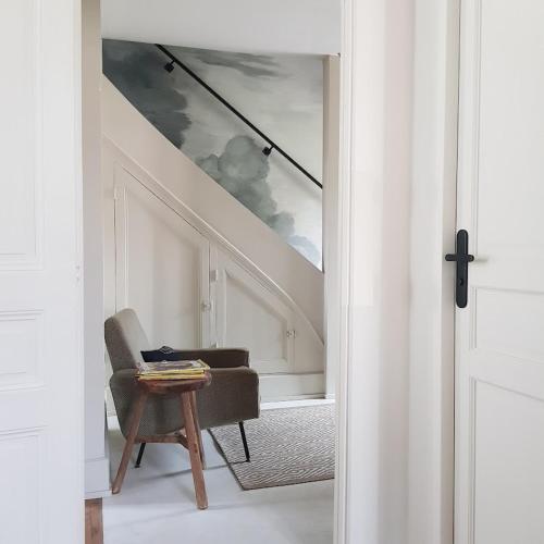 un salon avec une chaise et un escalier dans l'établissement la maison haute, à Toucy