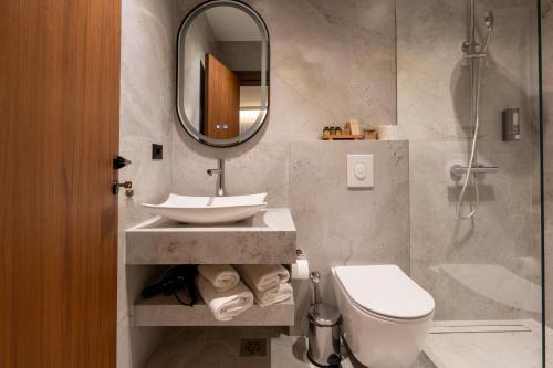 a bathroom with a sink and a toilet and a mirror at Ruby Hotel Prishtina in Pristina