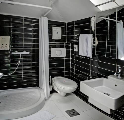a black tiled bathroom with a toilet and a sink at Hotel Boutique 36 in Sarajevo