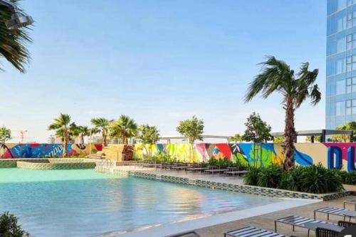 a pool at a resort with palm trees and a building at Aykon City 2 bedroom Burj view in Dubai
