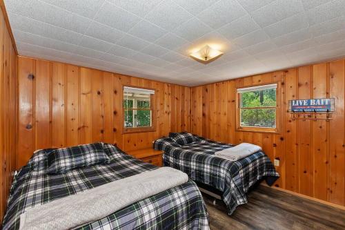 zwei Betten in einem Zimmer mit Holzwänden in der Unterkunft Applewood Cabins & Guest Cabin Near the Village in Big Bear Lake