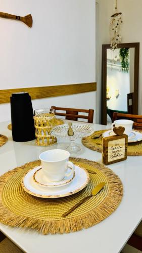 a table with plates and a cup and a bowl at Arraial Praia Ap - Residence Club Praia dos Anjos in Arraial do Cabo