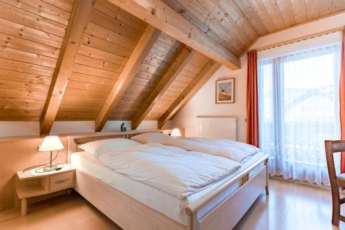 sypialnia z dużym łóżkiem i drewnianym sufitem w obiekcie Residence Villa Toni w mieście San Vigilio di Marebbe