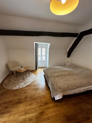 a bedroom with a bed and a table in it at Le Cottage du Domaine in Boissettes