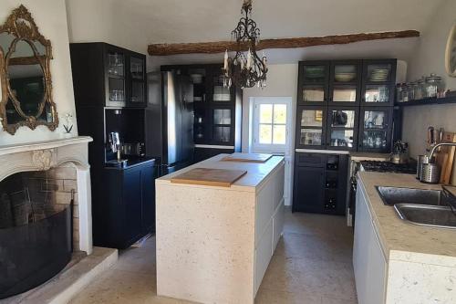 une grande cuisine avec des placards bleus et une cheminée dans l'établissement Village home in Ménerbes, à Ménerbes