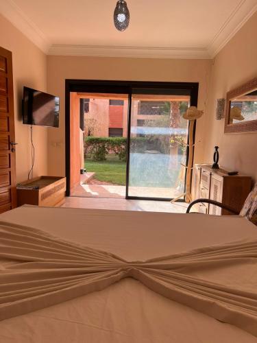 a bedroom with a bed and a sliding glass door at Appartement élégant avec vue sur piscine jardin verdoyant et wifi ultra rapide in Marrakech