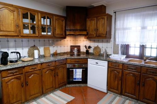 cocina con armarios de madera y lavavajillas blanco en Casa da Ondrinha, en Capinha