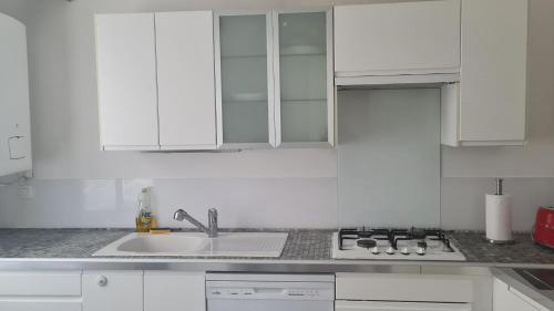 une cuisine blanche avec un évier et une cuisinière dans l'établissement Appartement nimes centre, à Nîmes