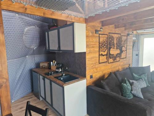 a kitchen with a couch in a tiny house at Namiot glampingowy Loft in Krzesimów