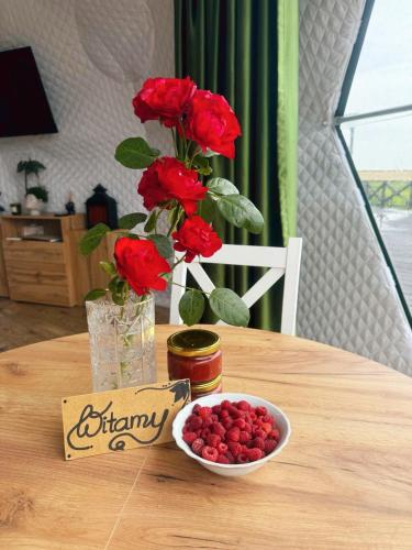 a table with a vase of roses and a bowl of berries at Namiot glampingowy Loft in Krzesimów