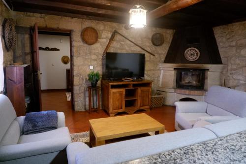 a living room with couches and a tv and a fireplace at Casa da Ondrinha in Capinha