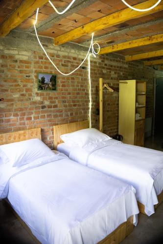 two beds in a room with a brick wall at Kazerma e Cerenit in Surrel