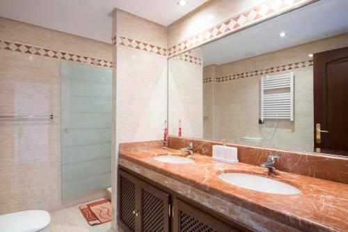 a bathroom with two sinks and a mirror at Luxury apartment with sea views, golf, gym, spa, 7 pools in Ojén