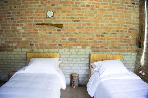 two beds in a room with a brick wall at Kazerma e Cerenit in Surrel