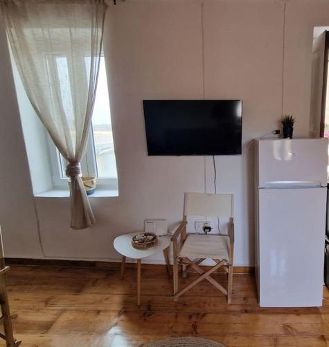 a kitchen with a white refrigerator and a table and chairs at To stegadaki - Traditional Cycladic Mansion in Ano Syros