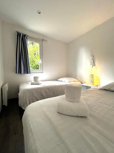 Cette chambre dispose de deux lits, d'une fenêtre et d'une chaise. dans l'établissement Les Chalets du Périgord, à Sarlat-la-Canéda