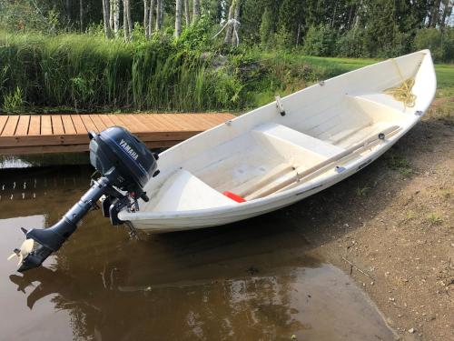 a white boat sitting on the water next to a dock at Villa Rantaniitty in Tampere