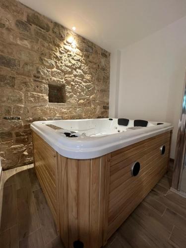 a bath tub in a room with a stone wall at Il Melograno in Civita Campomarano