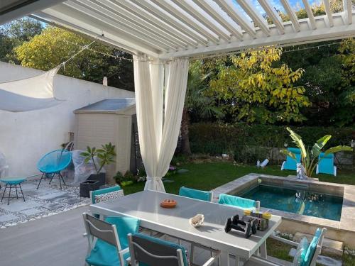 un patio avec une table et des chaises et une piscine dans l'établissement Le Mas de Fabregas Villa proche des plages, à La Seyne-sur-Mer