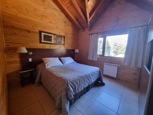 a bedroom with a bed in a wooden cabin at Encanto del Rio in Villa La Angostura