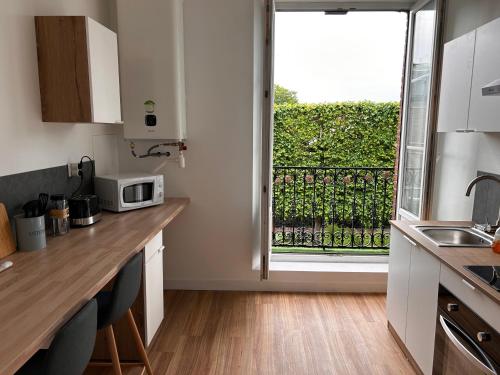 une cuisine avec un comptoir et une grande fenêtre dans l'établissement L apparté, à Beauvais