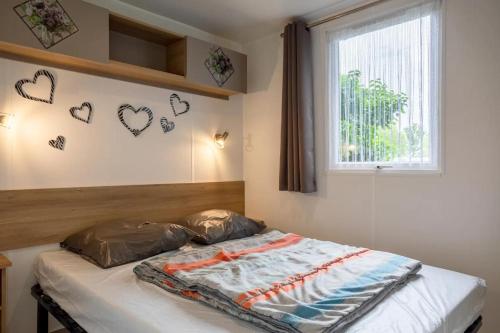 Ce lit se trouve dans une chambre dotée de cœurs sur le mur. dans l'établissement Mobil home 3 chambres Saint-Jean-de-Monts, à Saint-Jean-de-Monts