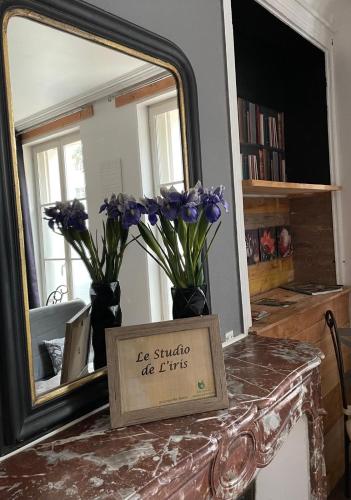 a mirror with vases with purple flowers on a table at L'Entre-Temps, Le Lys et L Iris in Saint-Aignan