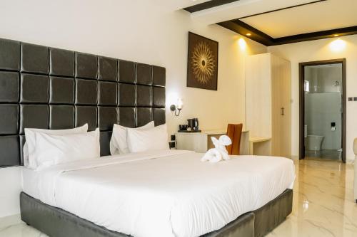 a bedroom with a large bed with a stuffed animal on it at Avian Court Hotel in Naivasha