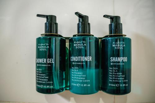 a group of three shampoo bottles sitting on a shelf at Avian Court Hotel in Naivasha