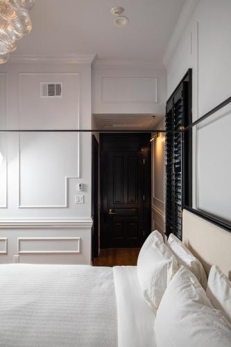 a bedroom with a white bed and a black door at Blackbird Hotel in New Orleans