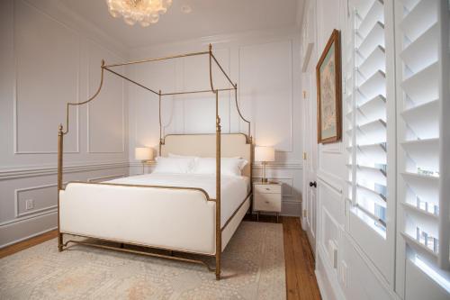 a white bedroom with a four poster bed at Blackbird Hotel in New Orleans