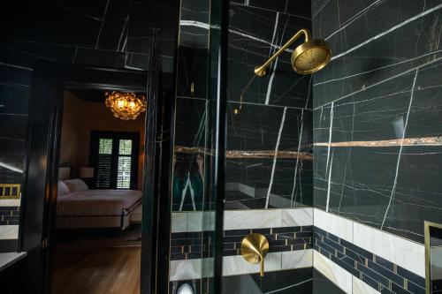 a bathroom with black tiled walls and a glass door at Blackbird Hotel in New Orleans