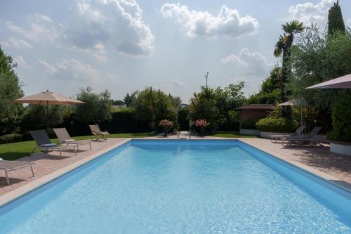 una grande piscina con sedie e ombrelloni di VILLA ELENA a Moniga