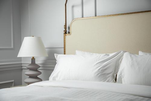 a bedroom with a bed with white pillows and a lamp at Blackbird Hotel in New Orleans