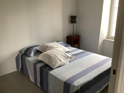 - un lit avec une couverture rayée bleue et blanche dans l'établissement La fontaine, à Cohade