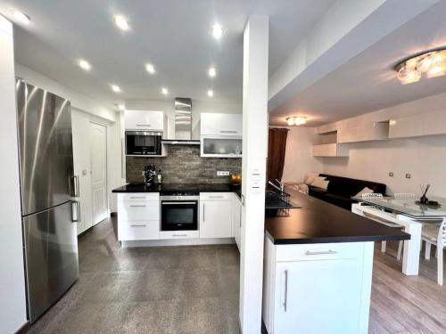 une cuisine avec des armoires blanches et un comptoir noir dans l'établissement Champs-Elysées - Arc de Triomphe - 2 pièces - 4p, à Paris