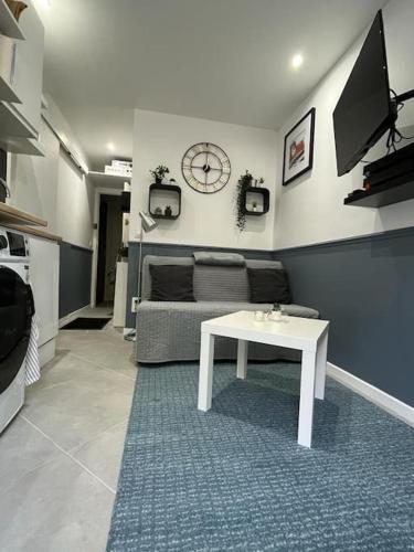- un salon avec une table, un canapé et un réveil dans l'établissement Studio Cosy à Fontenay le Fleury, à Fontenay-le-Fleury