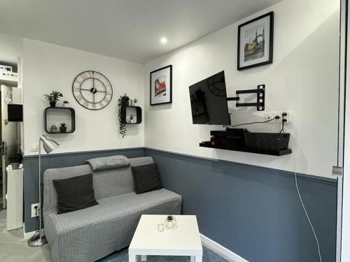 un salon avec un canapé et une horloge au mur dans l'établissement Studio Cosy à Fontenay le Fleury, à Fontenay-le-Fleury