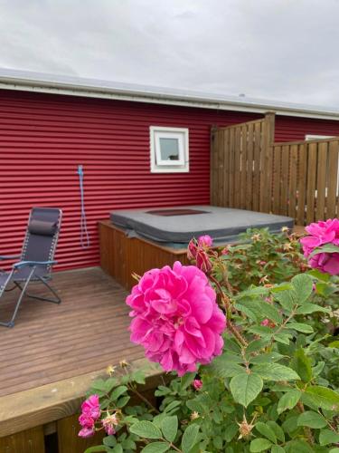 a deck with a bed and pink flowers at Norðurhof 5 845 Flúðir with private hot tube in Fludir